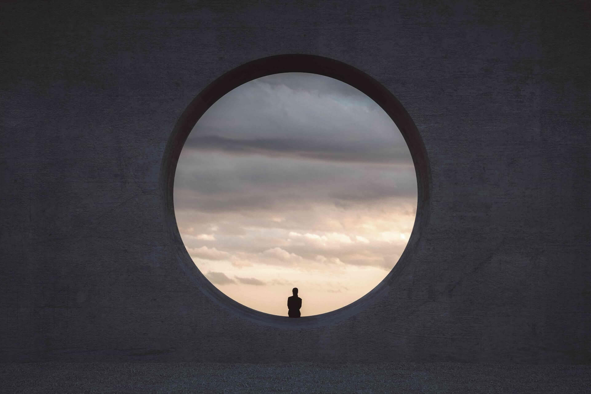 A person sit on a building looking in to the sky in the evening